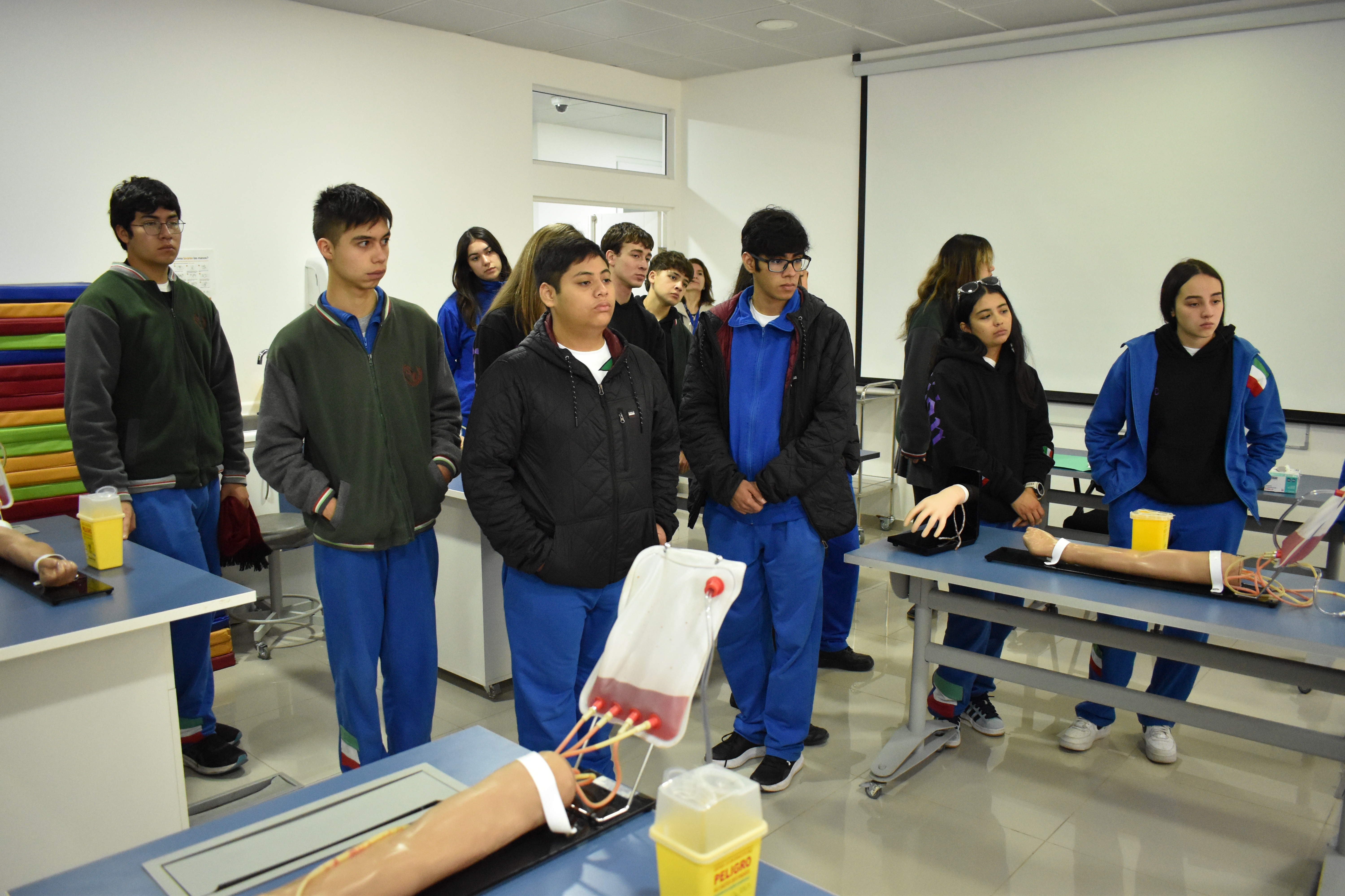 Alumnos de la Scuola Italiana de pie junto a simuladores de medicina